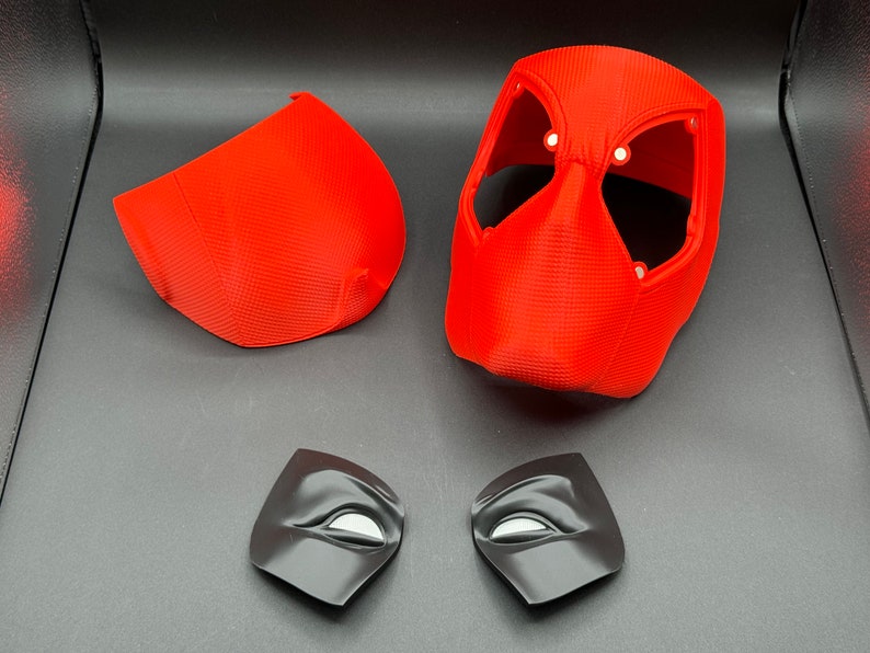 Puede incluir: Una m&aacute;scara de Deadpool de pl&aacute;stico rojo con dos piezas de ojos negras. La m&aacute;scara est&aacute; en cuatro piezas, con la parte principal de la m&aacute;scara, dos piezas laterales y dos piezas de ojos.