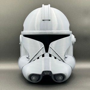 Puede incluir: Un casco de soldado clon gris de pl&aacute;stico con una visera. El casco tiene una superficie texturizada y est&aacute; dise&ntilde;ado para parecerse a un personaje de Star Wars.