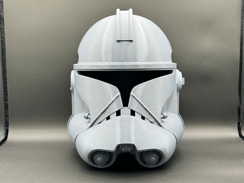 Puede incluir: Un casco de soldado clon gris de pl&aacute;stico con una visera. El casco tiene una superficie texturizada y est&aacute; dise&ntilde;ado para parecerse a un personaje de Star Wars.