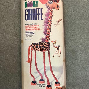 May include: Vintage "Kooky Giraffe" toy box. The box features a giraffe with a pink and brown head, a long neck, and red legs. The text on the box reads "Walking Kooky Giraffe" and "Stands approx. 24" tall."