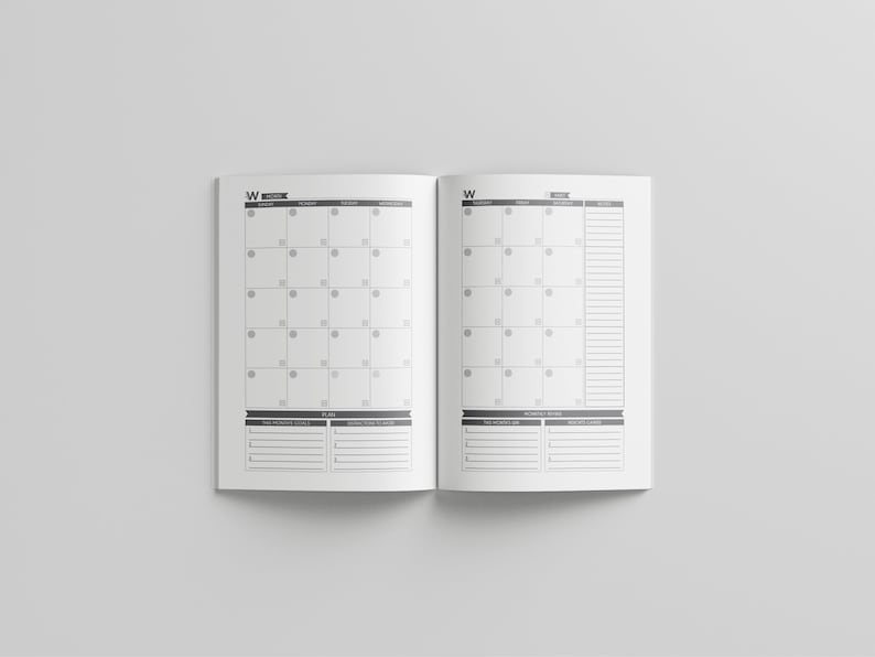 May include: Open planner with a monthly calendar layout. The pages are white with a gray grid for the calendar and space for notes. The planner is open to a month view with the days of the week across the top.