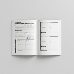 May include: Open, blank planner with black and white design. The left page has sections for daily tasks, mood, and focus. The right page has sections for tracking plans and reviews. The planner is open on a white surface.