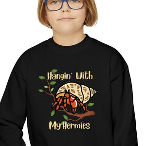 May include: Black long-sleeved sweatshirt with a graphic of a hermit crab in a shell on a branch. The text "Hangin' With My Hermies" is printed below the graphic.