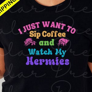 May include: Black t-shirt with the text "I just want to sip coffee and watch my hermies" in rainbow colors. The text is surrounded by two cartoon hermit crabs.