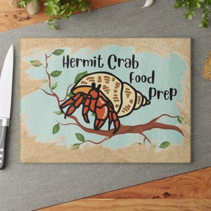 May include: A brown and beige cutting board with a cartoon hermit crab on a branch. The text "Hermit Crab Food Prep" is written on the board.