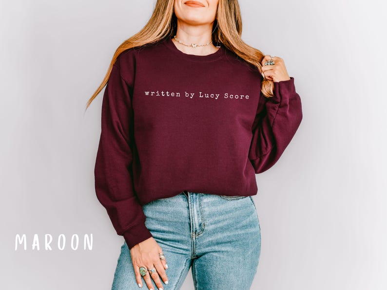 May include: A maroon sweatshirt with the text "written by Lucy Score" in white.