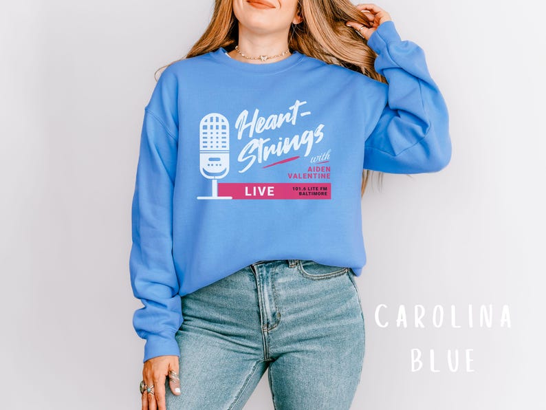 Puede incluir: Una sudadera azul con el texto "Heart-Strings with Aiden Valentine LIVE 101.5 Lite FM Baltimore" impreso en la parte delantera.