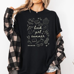 May include: Black t-shirt with a white graphic design of summer-themed doodles and the text "book girl summer".