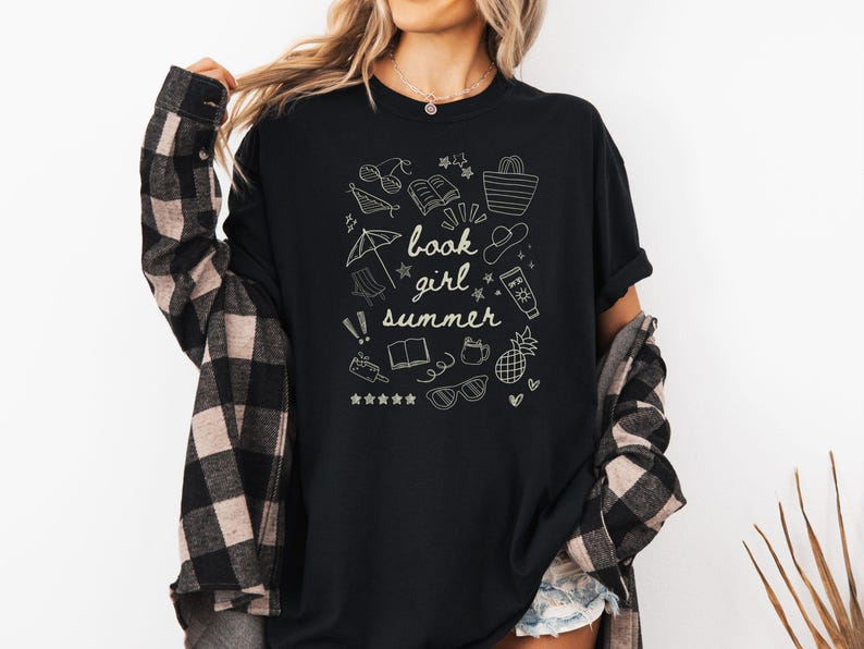 May include: Black t-shirt with a white graphic design of summer-themed doodles and the text "book girl summer".