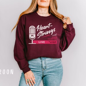 Puede incluir: Sudadera color granate con un gr&aacute;fico blanco de un micr&oacute;fono y el texto "Heart-Strings with Aiden Valentine 101.5 Lite FM Baltimore LIVE".