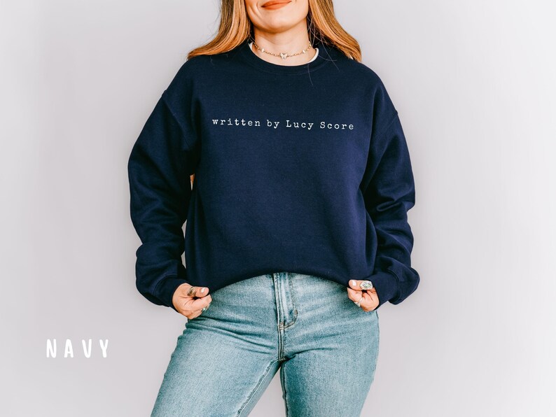 May include: A navy blue sweatshirt with the text "written by Lucy Score" in white on the front.