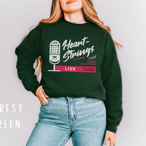 Puede incluir: Una sudadera verde bosque con el texto "Heart-Strings with Aiden Valentine 101.3 Lite FM Baltimore LIVE" y un gr&aacute;fico de micr&oacute;fono.