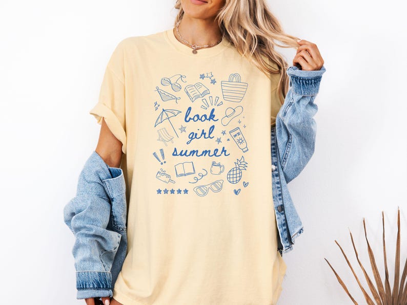 May include: A yellow t-shirt with a blue graphic design of summer-themed doodles and the text "book girl summer".