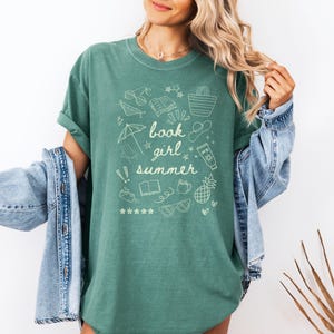 May include: A green t-shirt with a white graphic design of summer-themed doodles and the text "book girl summer".