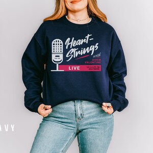 Puede incluir: Sudadera azul marino con un gr&aacute;fico blanco de un micr&oacute;fono y el texto "Heart-Strings with Aiden Valentine 101.5 Lite FM Baltimore LIVE".