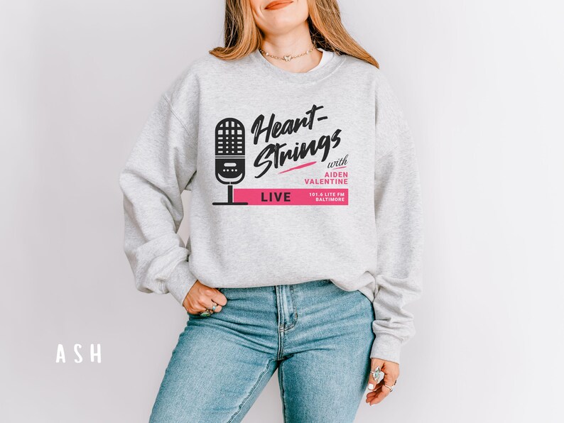 Puede incluir: Una sudadera gris con el texto "Heart-Strings with Aiden Valentine 101.3 Lite FM Baltimore LIVE" impreso en la parte delantera. El texto est&aacute; en negro y rosa.