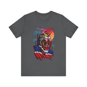 May include: A dark gray t-shirt with a graphic of a panther wearing a football helmet. The panther is in a red, white, and blue color scheme. The background is a sunset with palm trees.