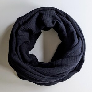 Könnte beinhalten: Ein dunkelmarinefarbener Rundschal aus weichem, strukturiertem Stoff. Der kreisförmige Schal ist gefaltet und drapiert, wodurch sein Design und Material hervorgehoben werden. Ein vielseitiges Accessoire.