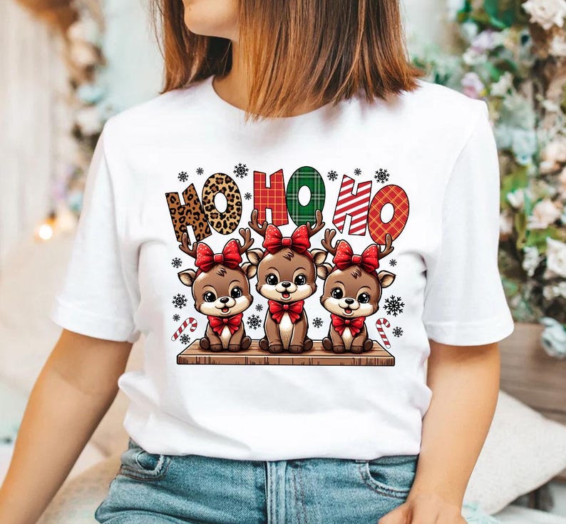 May include: White t-shirt with a Christmas design featuring three cartoon reindeer with red bows and the text "HO HO HO" in a plaid pattern.