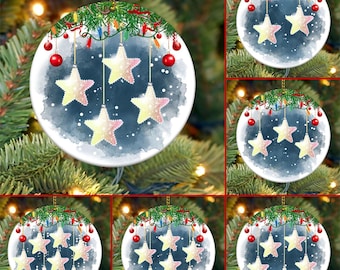 May include: Six round ceramic Christmas ornaments with a watercolor design of a night sky with five stars hanging from a string of lights. The stars are yellow with pink accents.