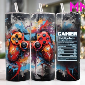 Puede incluir: Un diseño abstracto colorido con un mando de videojuegos rojo y negro en el centro. El diseño está en un vaso blanco con una tapa negra y una pajita transparente. El texto "GAMER Nutrition Facts" está en el lado derecho del vaso con una lista de "Nutrition Facts" para jugadores.