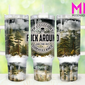 May include: A stainless steel tumbler with a camouflage design and the text "Protected by...F*ck Around and Find Out...Surveillance". The tumbler has a black skull and crossbones graphic and a white handle.