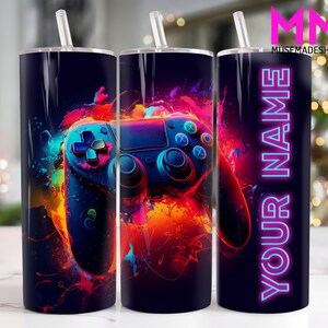 May include: A black and white tumbler featuring a colourful video game controller graphic and the text "YOUR NAME" in neon pink.