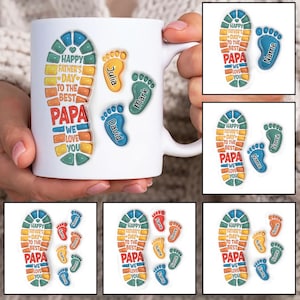 Puede incluir: Taza de cerámica blanca con un diseño de huella de pie colorido. La huella de pie dice "Feliz Día del Padre al mejor papá Te queremos". Hay tres huellas de pie más pequeñas con los nombres "Julia", "David" y "Mark" en la taza.