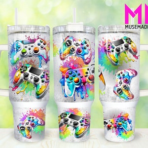 May include: Three white tumblers with a handle, featuring a colorful design of video game controllers with paint splatters. The tumblers are made of stainless steel and have a double-wall insulated design.