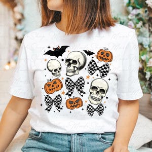 Może przedstawiać: Biała koszulka z nadrukiem w stylu Halloween z czaszkami, dyniami i czarno-białymi kokardkami w kratkę.