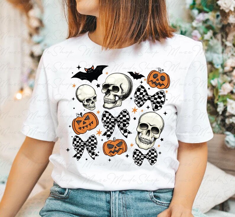 Może przedstawiać: Biała koszulka z nadrukiem w stylu Halloween z czaszkami, dyniami i czarno-białymi kokardkami w kratkę.