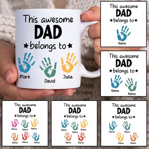 Może przedstawiać: Biały kubek ceramiczny z tekstem "This awesome DAD belongs to" i trzema odciskami dłoni z nazwami Mark, David i Julia pod spodem. Kubek jest pokazany w różnych wariantach z różnymi odciskami dłoni i nazwami.