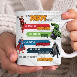May include: White ceramic mug with a colorful design featuring superheroes. The text reads "To my Daddy you are... as smart as Iron Man, as strong as Hulk, as fast as Superman, as brave as Batman, you are my favorite Superhero."
