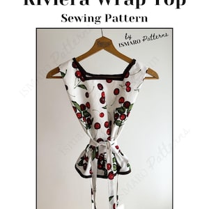 May include: A white wrap top sewing pattern with a cherry print, square neckline, and brown trim. The top is tied at the waist and hangs on a wooden hanger. Text at the top reads "The Riviera Wrap Top Sewing Pattern".