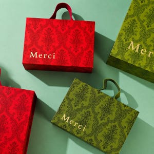 May include: Rectangular gift bags with handles, featuring a repeating damask pattern. Two bags are red with gold text reading Merci, and two bags are olive green with gold text reading Merci. The bags are arranged in a group on a flat surface.