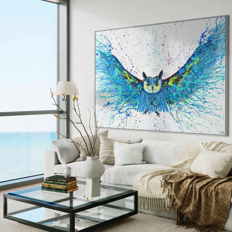 May include: A blue and green owl with its wings spread wide, painted in a splatter style on a white canvas. The owl's eyes are yellow and its beak is orange. The background is white with splashes of blue, green, and yellow paint.