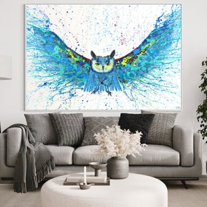 May include: A blue and green owl with its wings spread wide, painted in a splatter style on a white background. The owl's eyes are black and yellow, and its beak is orange. The painting is framed in a white frame.