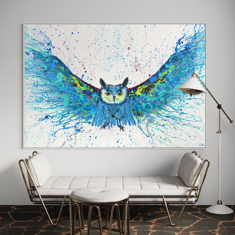 May include: A blue and green owl with its wings spread wide, painted in a splatter style on a white background. The owl's eyes are yellow and its beak is black. The painting is framed in a white frame.
