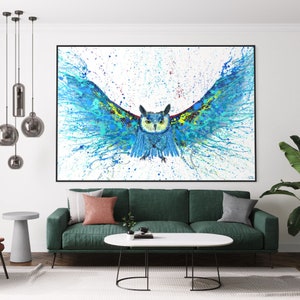 May include: A blue and green owl with its wings spread wide, painted in a splatter style on a white background. The owl is facing forward with its eyes open and its beak closed. The painting is framed in black.