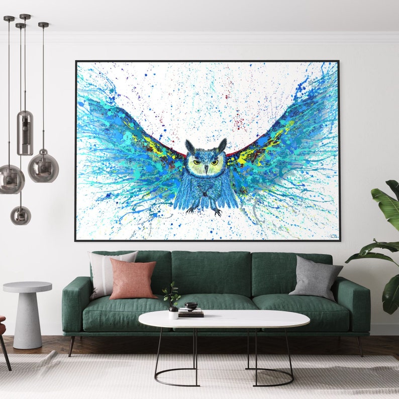 May include: A blue and green owl with its wings spread wide, painted in a splatter style on a white background. The owl is facing forward with its eyes open and its beak closed. The painting is framed in black.