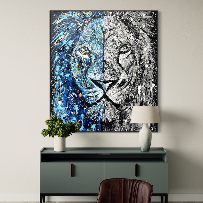 以下が含まれることがあります： 青と白の塗料の飛沫がついたライオンの顔の抽象画。ライオンの顔は半分に割れており、片側は青、もう片側は白です。