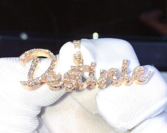 May include: A rose gold pendant spelling out the name "Destinie" in a cursive font. The pendant is encrusted with small, sparkling clear stones. The jewelry is displayed against a white background.