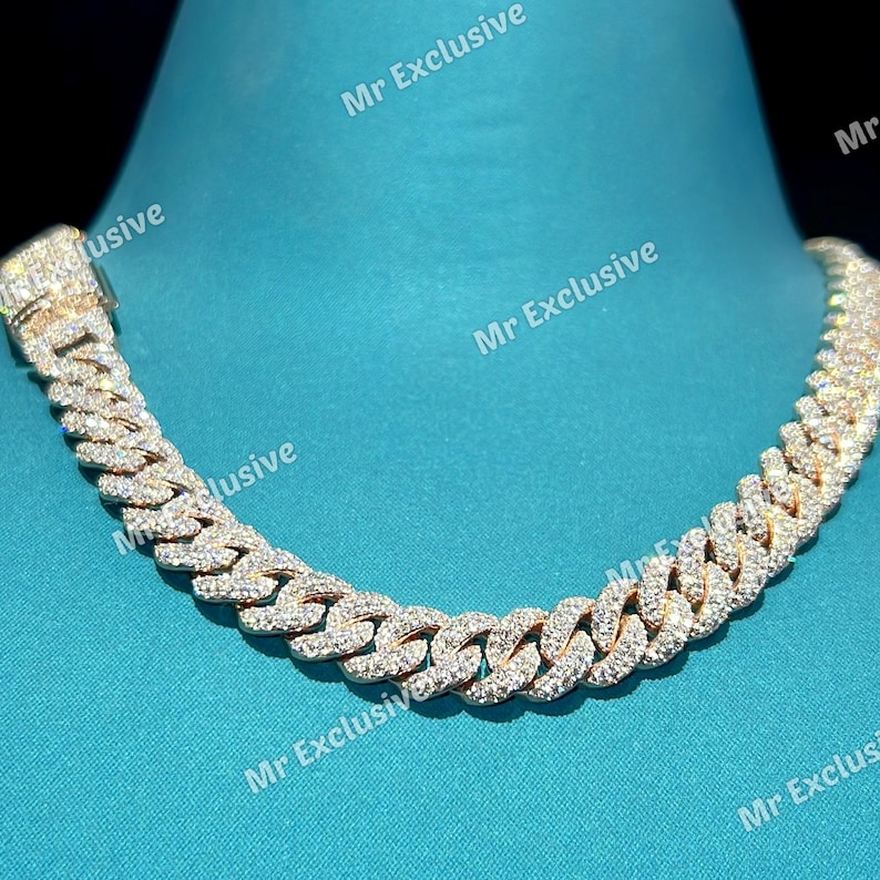 May include: A gold-toned cuban link chain necklace, encrusted with numerous small, clear gemstones. The necklace is displayed against a teal background. The text "Mr Exclusive" is watermarked across the image.