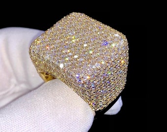 May include: A gold ring with a square face covered in small, sparkling diamonds.
