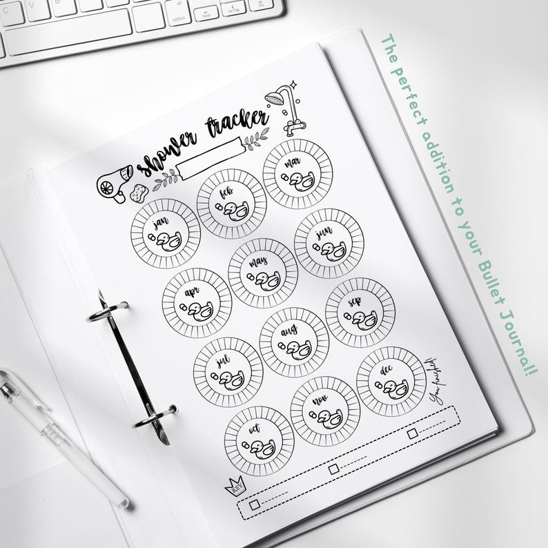 May include: A printable shower tracker with a black and white design. The tracker features a shower head, a hairdryer, and a duck for each month of the year. The text "shower tracker" is written in cursive at the top of the page. The text "The perfect addition to your Bullet Journal!" is written in green cursive on the right side of the page.