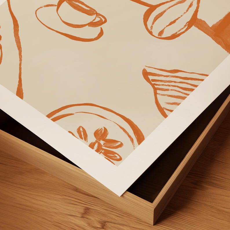 May include: A framed art print featuring orange line drawings of a cup and saucer, a bowl with a flower, and other abstract shapes on a cream background. The print is set in a natural wood frame.
