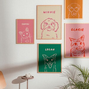 K&ouml;nnte beinhalten: Eine Sammlung gerahmter Tierportr&auml;ts mit Katzen und Hunden. Jeder Druck hat einen eindeutigen Tiernamen in fetter Schrift, mit der Umrisslinie des Tieres in einer Kontrastfarbe. Die Farbpalette umfasst Rosa, Gr&uuml;n und Orange, mit neutral get&ouml;nten Rahmen.