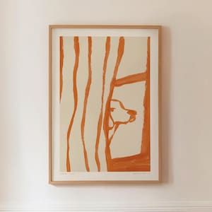 Puede incluir: Una impresión artística enmarcada con una ilustración abstracta de la cabeza de un perro asomándose por una ventana. La obra de arte utiliza tonos naranja y crema, con pinceladas verticales naranjas a la izquierda. La impresión está en un marco de madera.