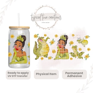 Puede incluir: Un vaso de vidrio transparente con tapa de madera y pajita, con una imagen de dibujos animados de una princesa con un vestido verde y una corona, rodeada de flores amarillas. La imagen está lista para ser aplicada al vaso mediante una transferencia UV DTF.