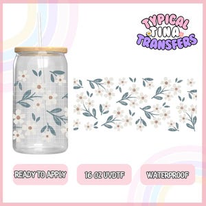May include: A 16 ounce clear glass tumbler with a bamboo lid and a straw. The tumbler has a white and blue floral pattern with small white flowers and blue leaves. The text "READY TO APPLY", "16 OZ UVDTIF", and "WATERPROOF" are visible below the tumbler.